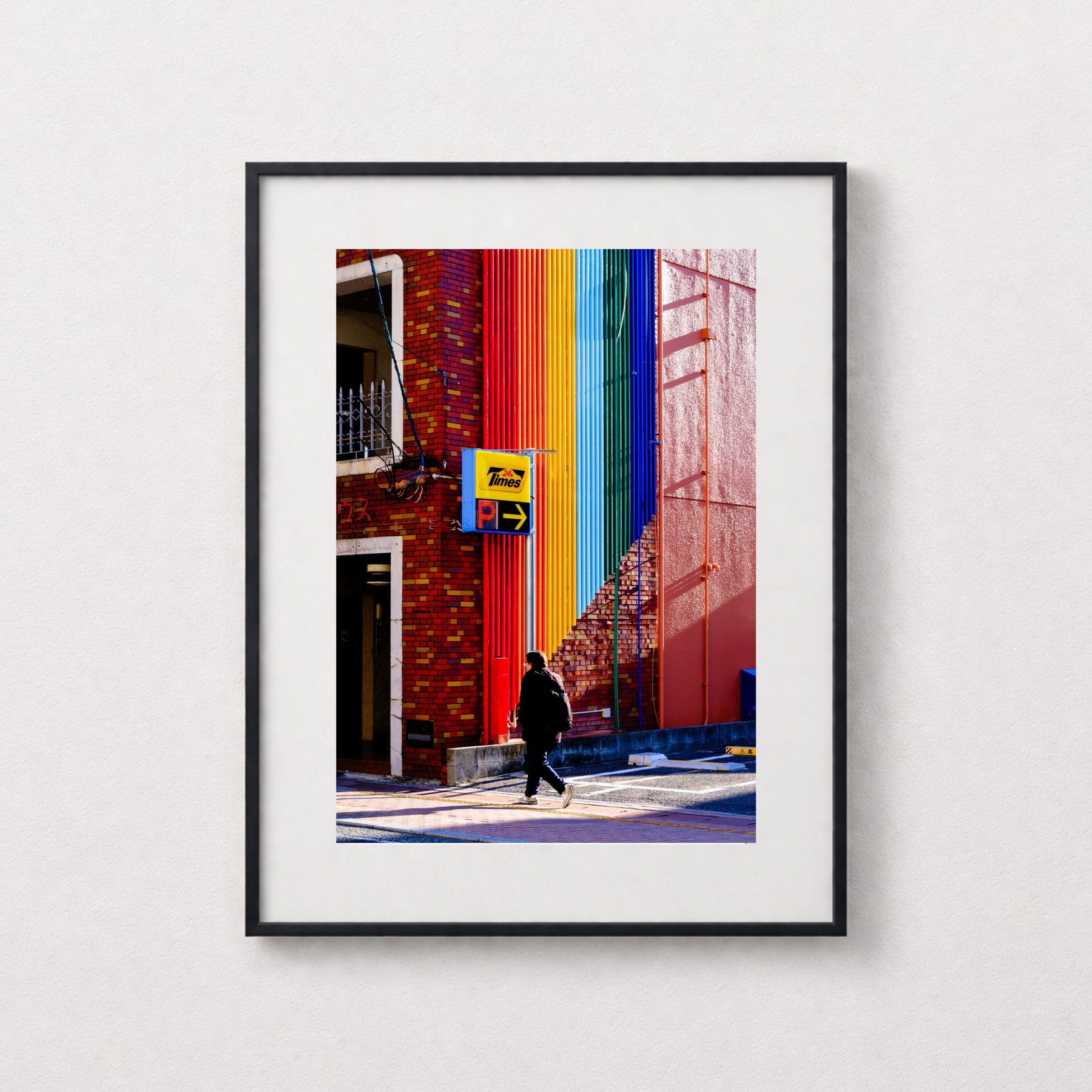 Rainbow shown in a black frame against a grey wall.